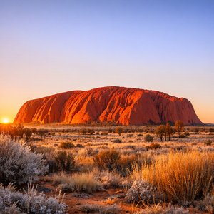 Uluru beim Sonnenaufgang — warmes Licht auf rotem Fels